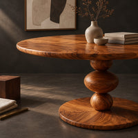 Corner detail of round dining table with a pedestal of three stacked orbs beside wood, brass and linen samples
