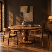 Round dining table with a pedestal of three stacked orbs in a dark dining room at golden hour