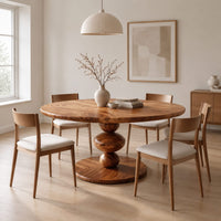 Round dining table with a pedestal of three stacked orbs in a Scandinavian dining room with white walls
