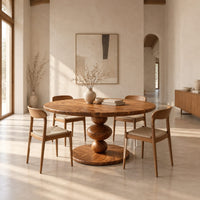 Round dining table with a pedestal of three stacked orbs in a bright open plan dining room