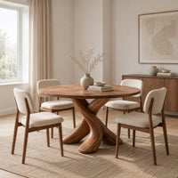 Circular dining table with two crossed branch shaped legs and wide curved feet in a Scandinavian dining room with white walls