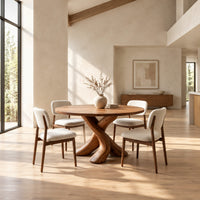 Circular dining table with two crossed branch shaped legs and wide curved feet in a bright open plan dining room