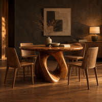 Circular dining table on a sculpted pedestal with a large open loop in a dark dining room at golden hour
