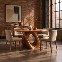 Circular dining table on a sculpted pedestal with a large open loop in an industrial loft dining room with exposed brick