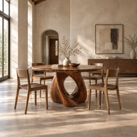 Circular dining table on a sculpted pedestal with a large open loop in a bright open plan dining room