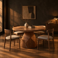Circular dining table with a faceted bell shaped pedestal base in a dark dining room at golden hour