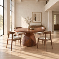 Circular dining table with a faceted bell shaped pedestal base in a bright open plan dining room