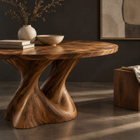 Corner detail of round dining table on a twisted pedestal base beside wood, brass and linen samples