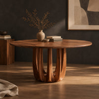 Corner detail of round dining table on a pedestal made of arched wood columns beside wood, brass and linen samples