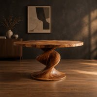 Round dining table with a spiral twist pedestal base and a wide flat foot in a dark studio against a charcoal plaster wall