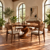 Round dining table with a spiral twist pedestal base and a wide flat foot in a bright dining room with arched windows and plants