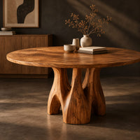 Corner detail of circular dining table on branching arched pedestal legs beside wood, brass and linen samples