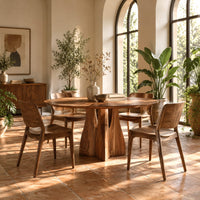 Round dining table with a flared sculpted pedestal base in a bright dining room with arched windows and plants