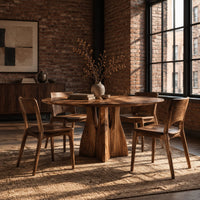 Round dining table with a flared sculpted pedestal base in an industrial loft dining room with exposed brick