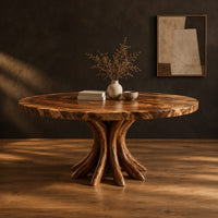 Circular dining table with a swirl grain top and flared trunk shaped legs in a dark studio against a charcoal plaster wall