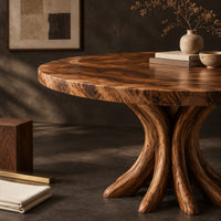 Corner detail of circular dining table with a swirl grain top and flared trunk shaped legs beside wood, brass and linen samples