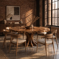 Circular dining table with a swirl grain top and flared trunk shaped legs in an industrial loft dining room with exposed brick
