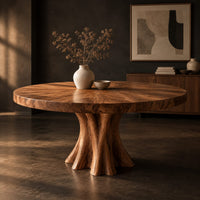 Corner detail of round dining table with a thick flared pedestal base beside wood, brass and linen samples