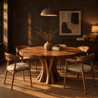 Round dining table with a thick flared pedestal base in a dark dining room at golden hour