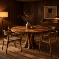 Round dining table with a thick flared pedestal base in an evening dining room with walnut wall paneling