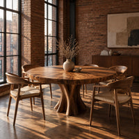 Round dining table with a thick flared pedestal base in an industrial loft dining room with exposed brick