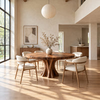 Round dining table with a thick flared pedestal base in a bright open plan dining room