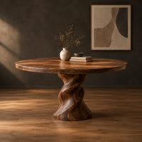 Round wooden dining table on a twisted pedestal base in a dark studio against a charcoal plaster wall