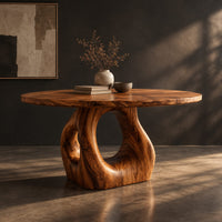 Circular wooden dining table on a sculpted pedestal with an open oval center, three-quarter view showing the grain