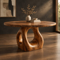 Corner detail of circular wooden dining table on a sculpted pedestal with an open oval center beside wood, brass and linen samples