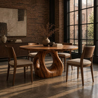Circular wooden dining table on a sculpted pedestal with an open oval center in an industrial loft dining room with exposed brick