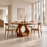 Circular wooden dining table on a sculpted pedestal with an open oval center in a bright open plan dining room