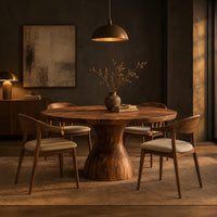 Round dining table with an hourglass pedestal base in a dark dining room at golden hour