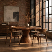 Round dining table with an hourglass pedestal base in an industrial loft dining room with exposed brick