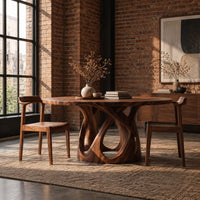 Round dining table on an open base of interlaced curves in an industrial loft dining room with exposed brick