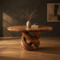 Round dining table with a twisted loop pedestal base in a dark studio against a charcoal plaster wall
