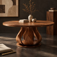 Corner detail of round dining table on a petal shaped pedestal with a low disc foot beside wood, brass and linen samples