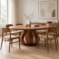 Round dining table on a petal shaped pedestal with a low disc foot in a Scandinavian dining room with white walls
