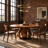 Round dining table on a petal shaped pedestal with a low disc foot in an industrial loft dining room with exposed brick