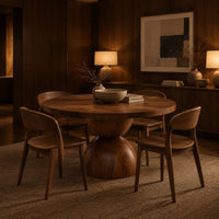 Round dining table with a radiating grain top and a sculpted hourglass base in an evening dining room with walnut wall paneling