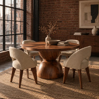 Round dining table with a radiating grain top and a sculpted hourglass base in an industrial loft dining room with exposed brick