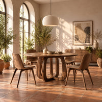Round dining table with a thick pedestal base of arched wooden loops in a bright dining room with arched windows and plants