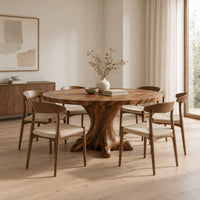 Circular dining table with a root shaped pedestal base in a Scandinavian dining room with white walls