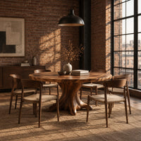 Circular dining table with a root shaped pedestal base in an industrial loft dining room with exposed brick