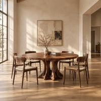 Round dining table with a radial grain top on a root like pedestal in a bright open plan dining room
