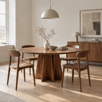 Round dining table with a sunburst grain top and a faceted star pedestal in a Scandinavian dining room with white walls