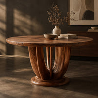 Corner detail of round dining table on a pedestal of tall arched wooden slats beside wood, brass and linen samples