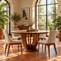 Round dining table on a pedestal of tall arched wooden slats in a bright dining room with arched windows and plants