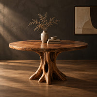 Circular dining table on a hollow tree trunk pedestal with spreading roots in a dark studio against a charcoal plaster wall