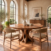 Circular dining table on a hollow tree trunk pedestal with spreading roots in a bright dining room with arched windows and plants