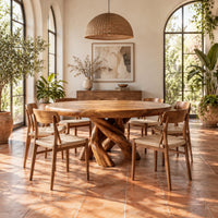 Round dining table with a twisted branch pedestal base in a bright dining room with arched windows and plants